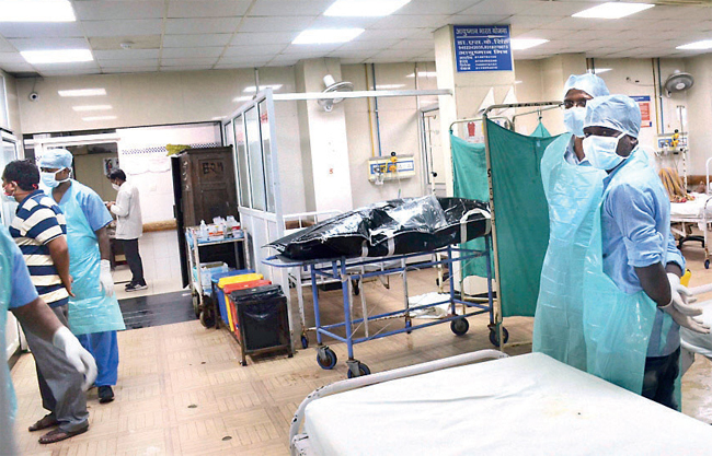Hospital staff stand next to the body of Vikas Dubey, in Kanpur